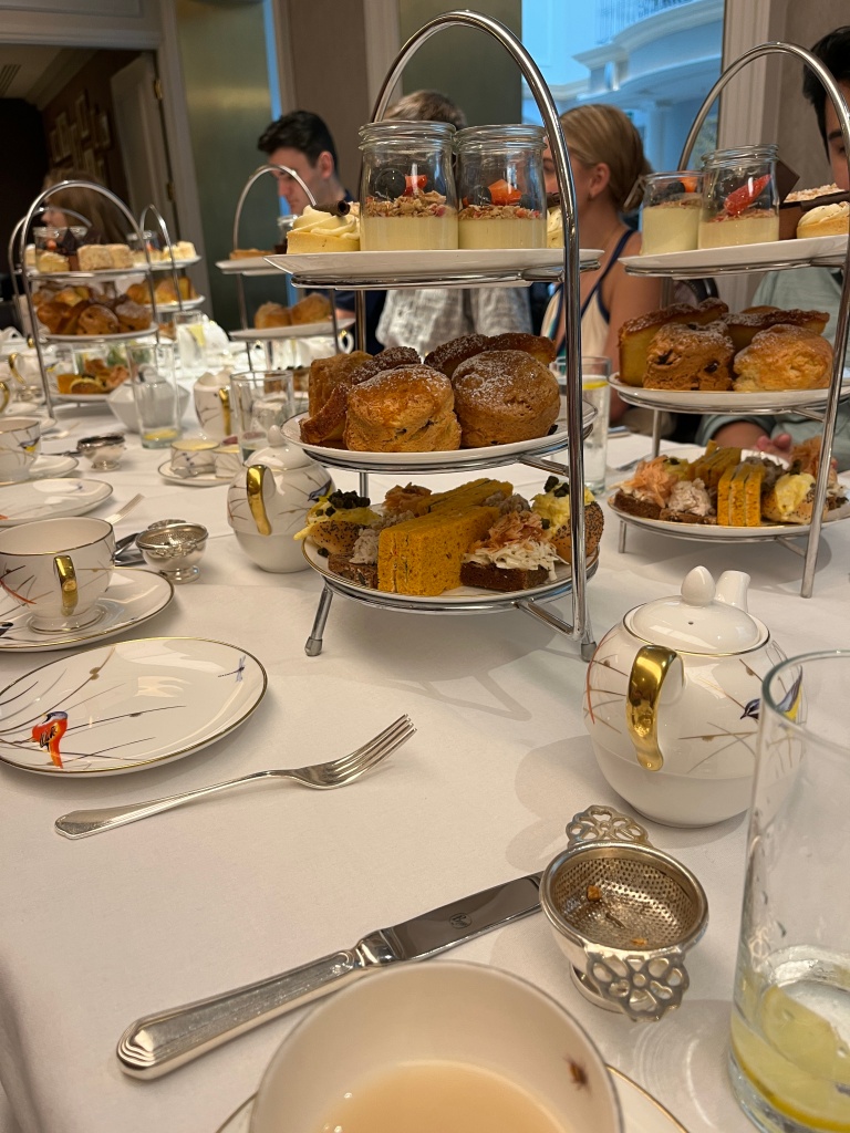 Three layers of high tea food and table settings with tea and plates
